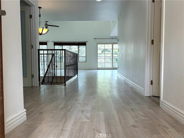 hall with an upstairs landing, baseboards, and wood finished floors