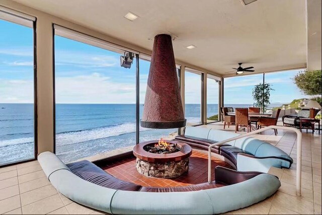 sunroom / solarium featuring a water view, ceiling fan, and a view of the beach