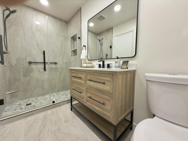 bathroom featuring vanity, a tile shower, and toilet