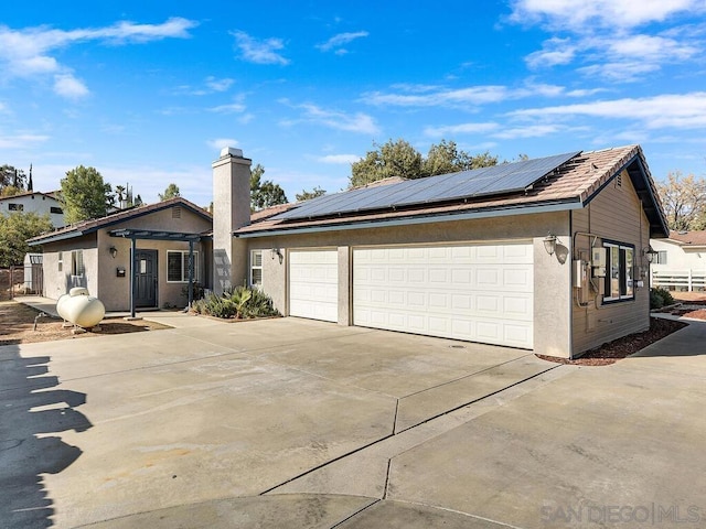 ranch-style home featuring a garage and solar panels