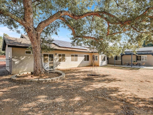 back of property with a patio and solar panels