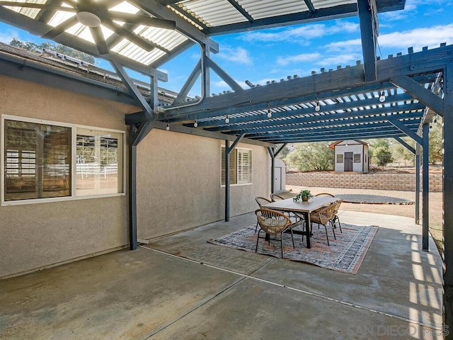 view of patio featuring a storage shed, ceiling fan, and a pergola