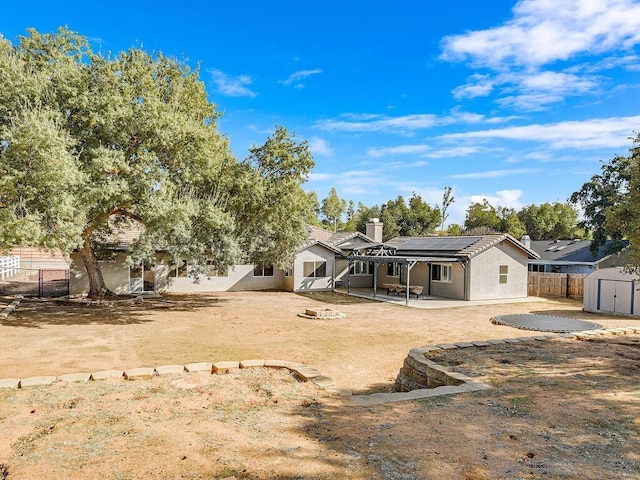 rear view of property with a storage shed, a fire pit, a patio area, and solar panels