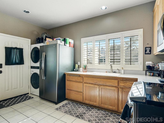 laundry area featuring sink, light tile patterned floors, and stacked washer and clothes dryer