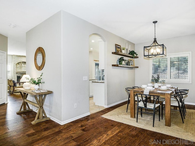 dining area featuring hardwood / wood-style floors, a notable chandelier, and a fireplace