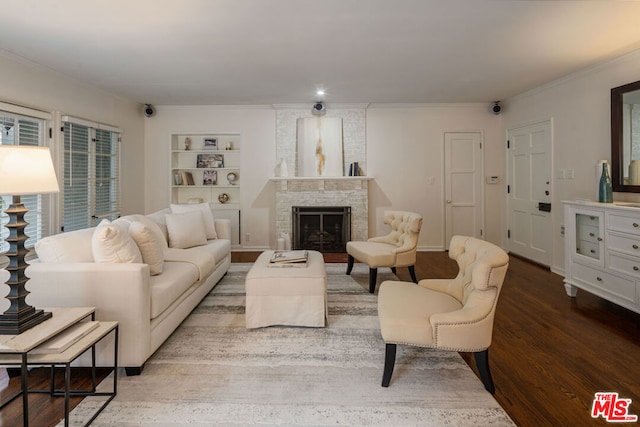 living room featuring wood-type flooring, ornamental molding, a fireplace, and built in shelves