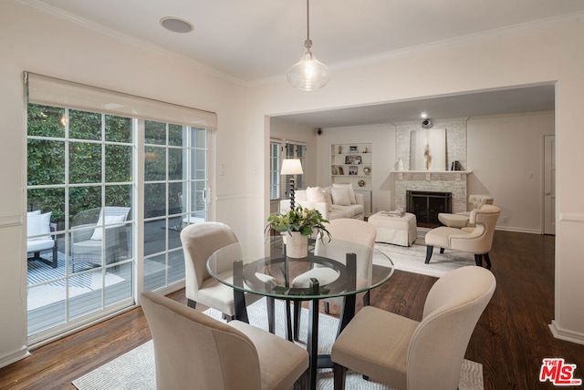 dining space with crown molding, a large fireplace, built in shelves, and hardwood / wood-style floors