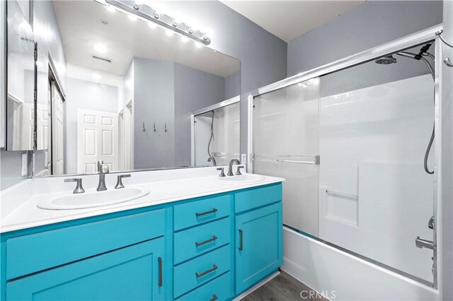 bathroom with vanity, hardwood / wood-style floors, and shower / bath combination with glass door