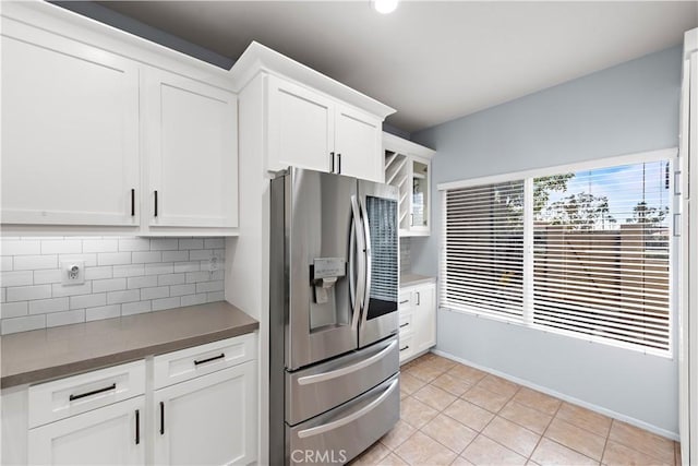 kitchen featuring white cabinetry, light tile patterned floors, decorative backsplash, and stainless steel fridge