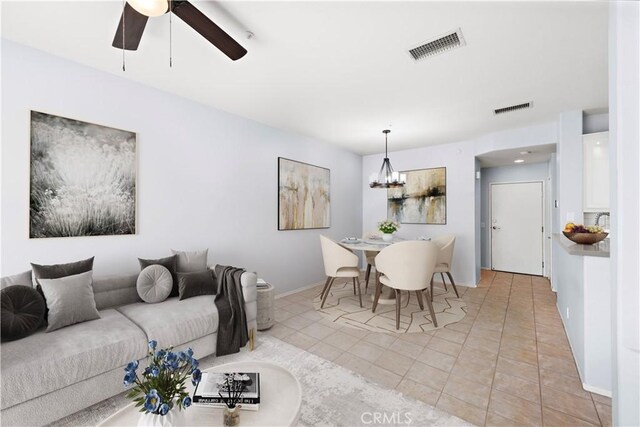 living room featuring light tile patterned floors and ceiling fan with notable chandelier