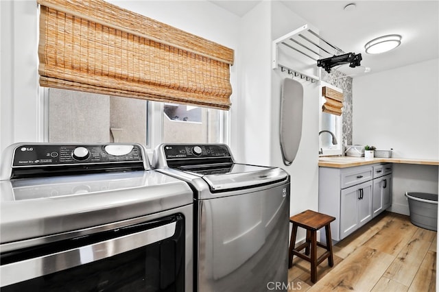 washroom with sink, light hardwood / wood-style flooring, and washing machine and clothes dryer