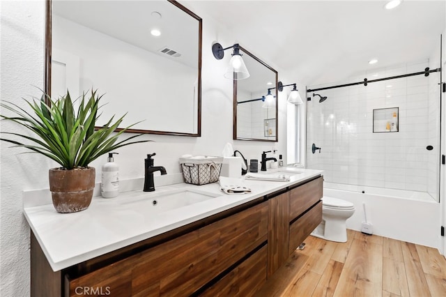 full bathroom featuring vanity, wood-type flooring, toilet, and tiled shower / bath