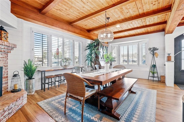 dining room with a brick fireplace, plenty of natural light, wooden ceiling, and light wood-type flooring