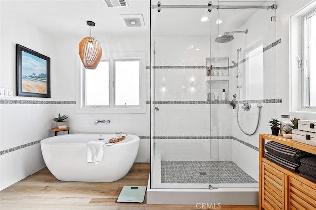 bathroom featuring tile walls, hardwood / wood-style floors, and plus walk in shower