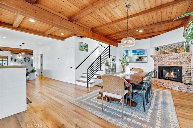 dining space featuring wood ceiling, a fireplace, beam ceiling, and light hardwood / wood-style flooring