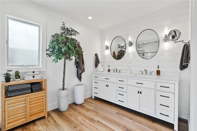 bathroom with wood-type flooring, wooden walls, and vanity