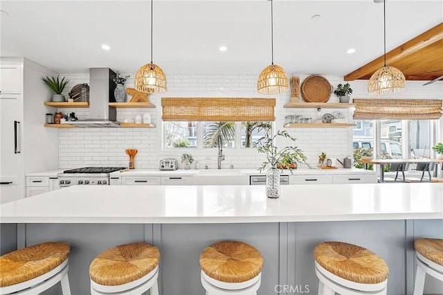 kitchen with hanging light fixtures, a kitchen bar, and wall chimney exhaust hood