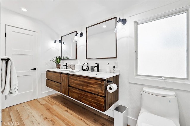 bathroom with wood-type flooring, toilet, and vanity