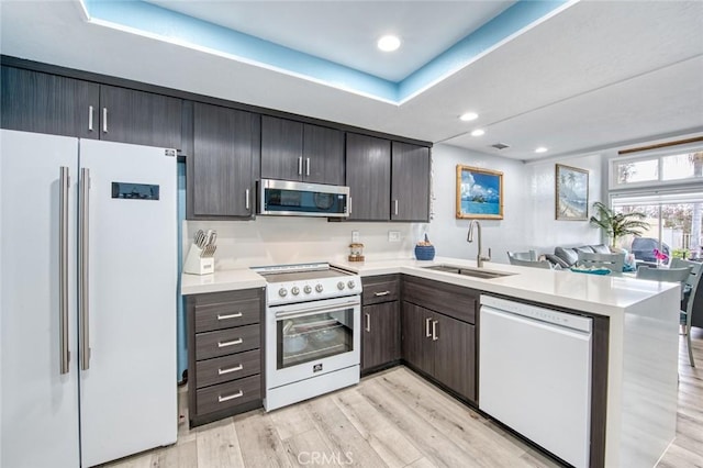 kitchen featuring sink, high quality fridge, white dishwasher, kitchen peninsula, and electric stove