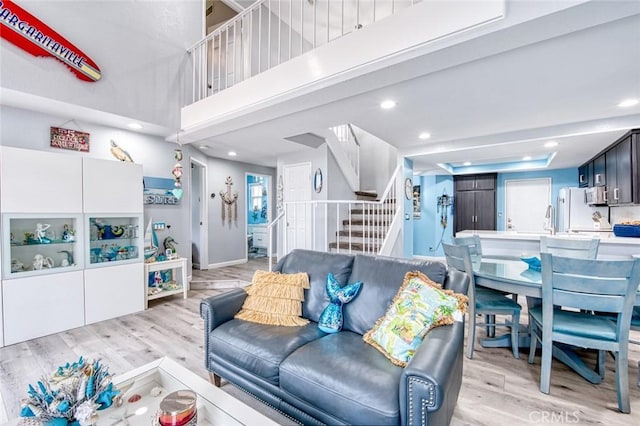 living room featuring sink, light hardwood / wood-style floors, and a high ceiling