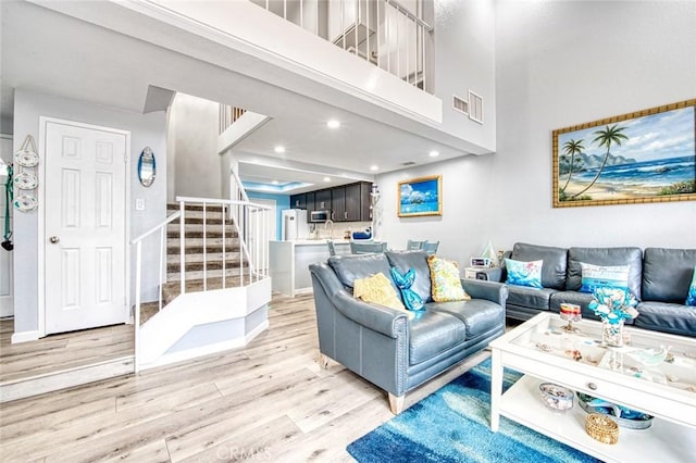 living room with light hardwood / wood-style floors and a high ceiling