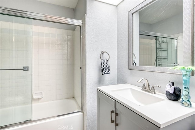 bathroom featuring bath / shower combo with glass door and vanity