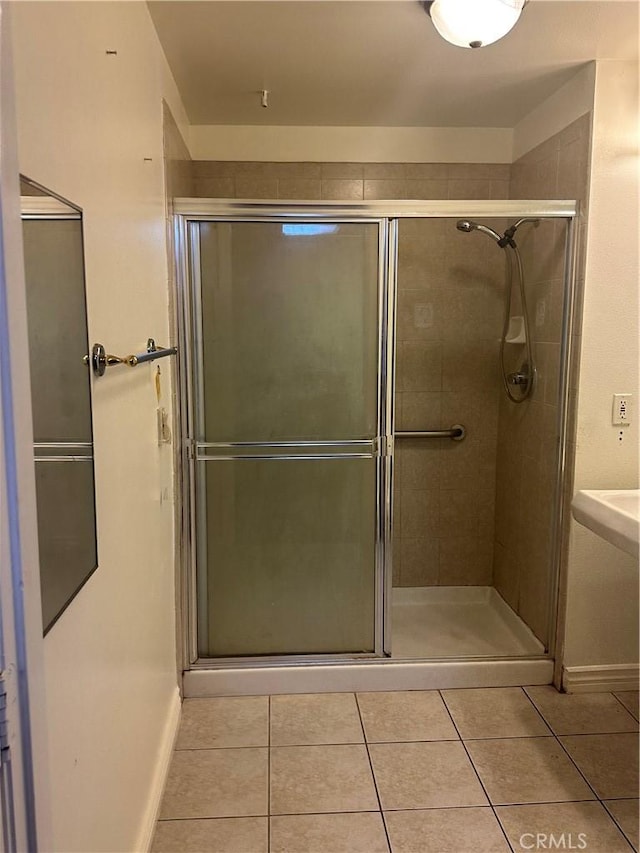 full bath featuring tile patterned floors, baseboards, and a stall shower