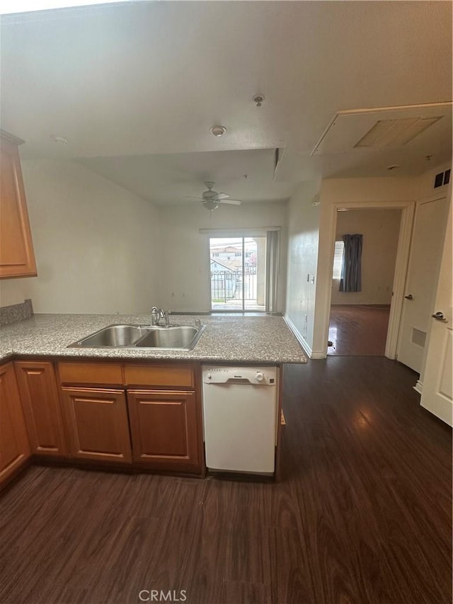 kitchen featuring visible vents, dark wood-type flooring, a sink, a peninsula, and white dishwasher