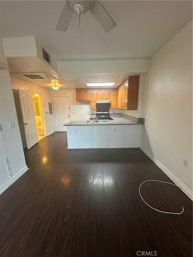 kitchen with visible vents, dark wood-type flooring, a ceiling fan, a peninsula, and baseboards