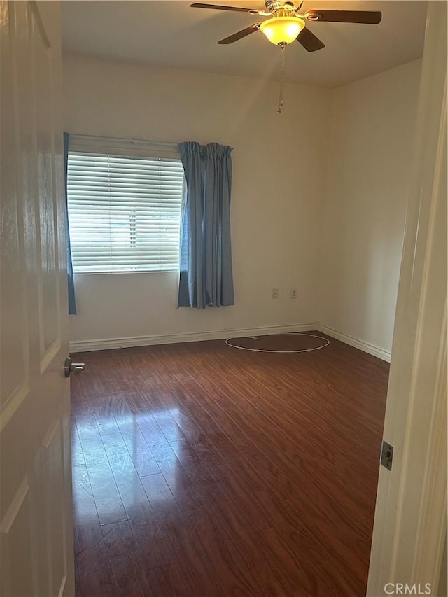 empty room with baseboards, wood finished floors, and a ceiling fan