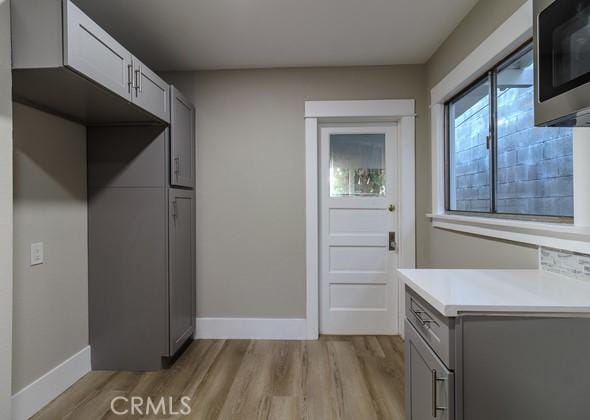 kitchen with gray cabinetry and light hardwood / wood-style floors