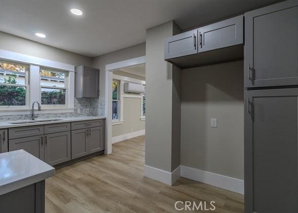 kitchen featuring tasteful backsplash, sink, gray cabinets, and light hardwood / wood-style floors