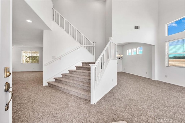 staircase featuring a wealth of natural light, carpet floors, and a high ceiling