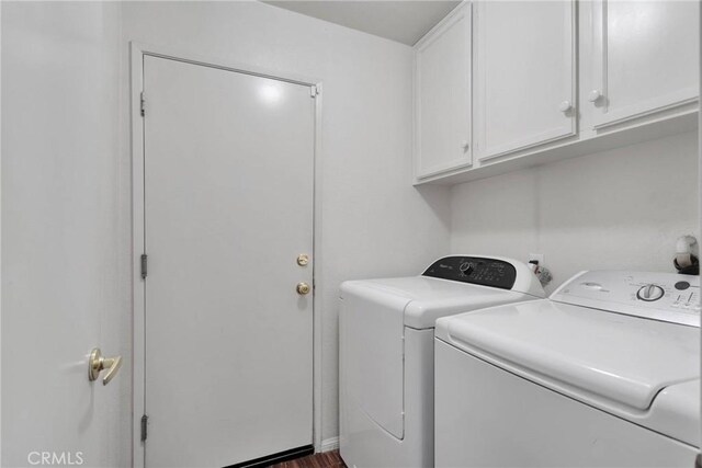 clothes washing area featuring dark hardwood / wood-style flooring, washer and clothes dryer, and cabinets