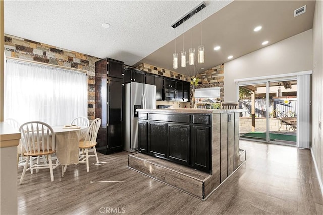 kitchen with pendant lighting, lofted ceiling, appliances with stainless steel finishes, a textured ceiling, and dark hardwood / wood-style flooring