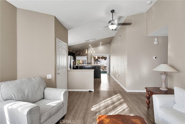 living room featuring a textured ceiling, wood-type flooring, ceiling fan, and vaulted ceiling