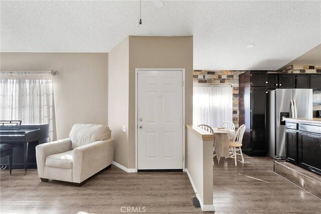 interior space featuring dark wood-type flooring, a textured ceiling, and stainless steel fridge with ice dispenser