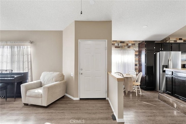 interior space with stainless steel fridge, dark hardwood / wood-style flooring, and a textured ceiling