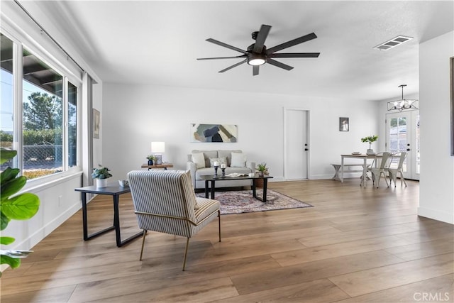 living room featuring hardwood / wood-style flooring and ceiling fan with notable chandelier