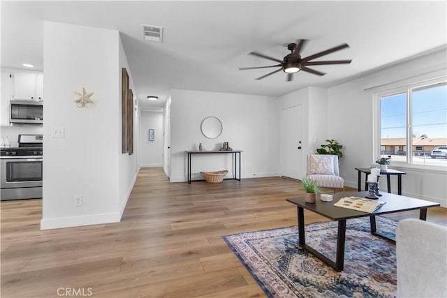 living room with light hardwood / wood-style flooring and ceiling fan