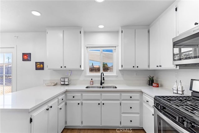 kitchen with sink, stainless steel appliances, kitchen peninsula, and white cabinets