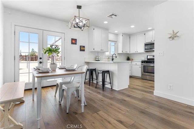 dining area with sink, dark wood-type flooring, french doors, and a chandelier