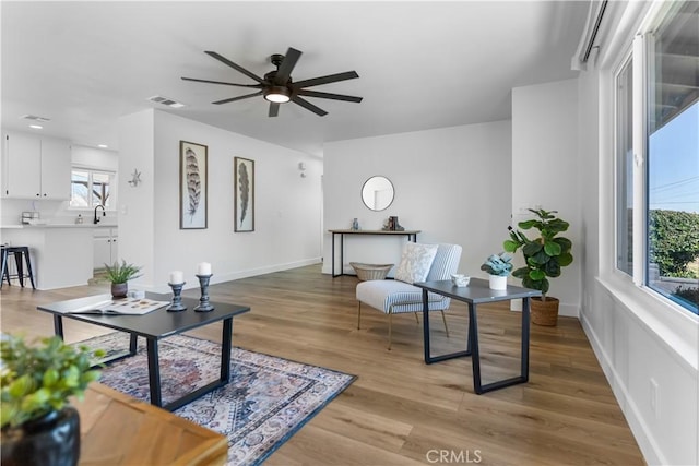 living room featuring sink, ceiling fan, and light wood-type flooring