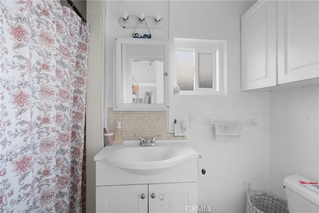 bathroom featuring vanity, backsplash, and toilet