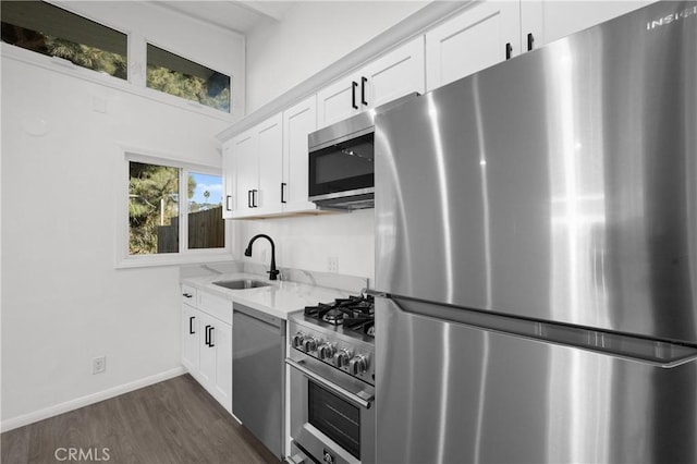 kitchen featuring sink, white cabinetry, appliances with stainless steel finishes, dark hardwood / wood-style floors, and light stone countertops