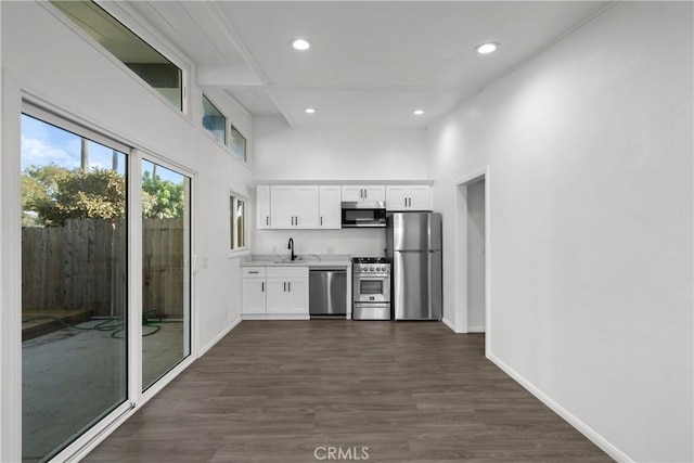 kitchen with sink, white cabinetry, a towering ceiling, stainless steel appliances, and dark hardwood / wood-style flooring