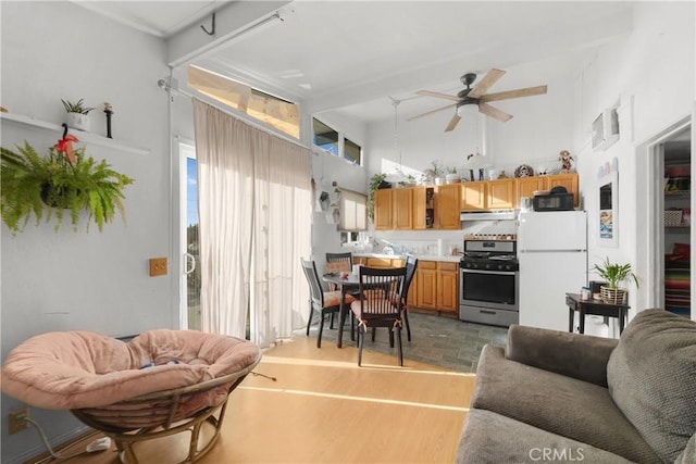 living room featuring ceiling fan, dark hardwood / wood-style floors, beam ceiling, and a high ceiling