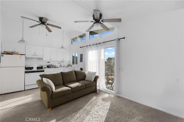 living room with ceiling fan, a towering ceiling, wood-type flooring, and sink