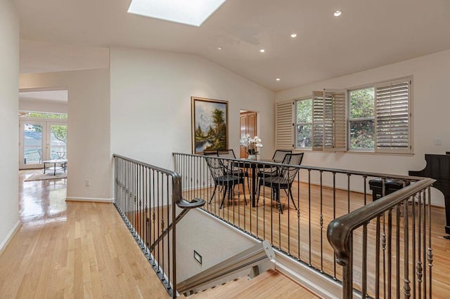 interior space with lofted ceiling with skylight and light hardwood / wood-style flooring