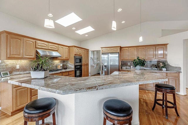 kitchen with a large island, a kitchen bar, decorative light fixtures, and appliances with stainless steel finishes